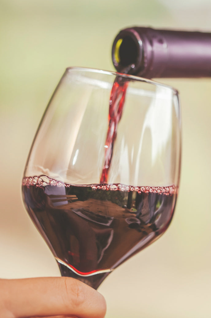 A bottle of concord being poured in a glass