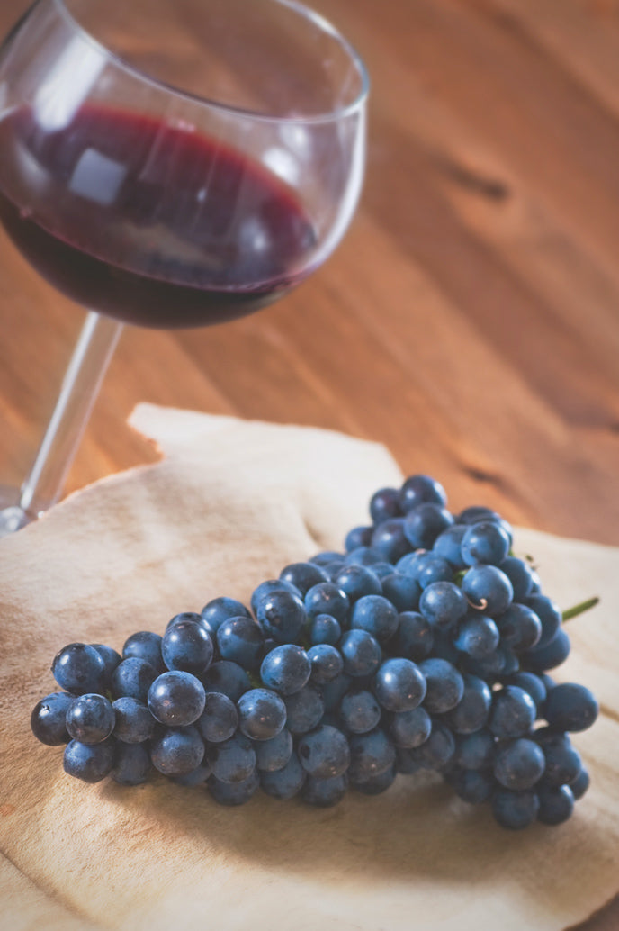 A glass of Shiraz beside fresh grapes