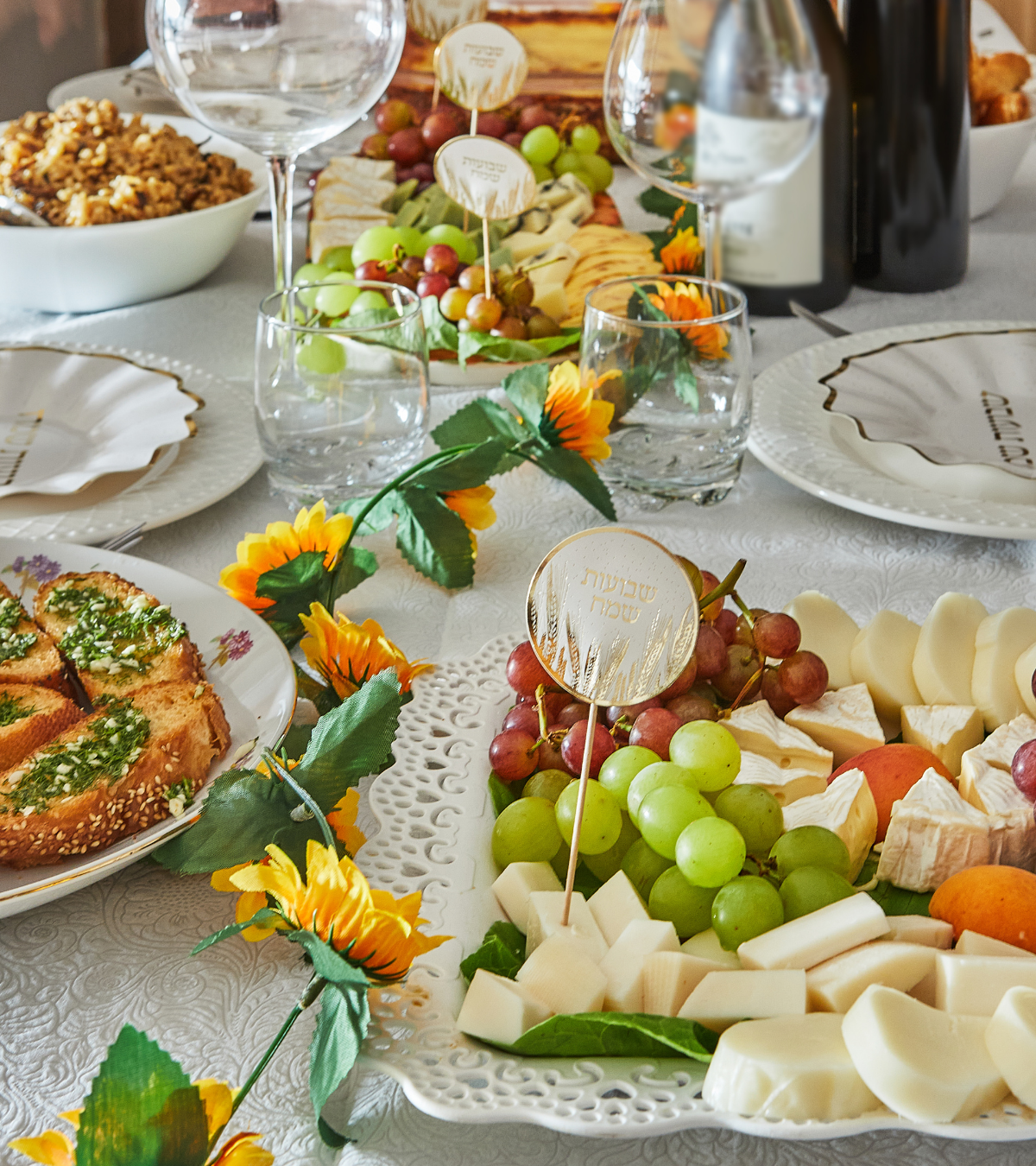 An elegant Shavuot holiday table with wine. cheese, fruit, and holiday decorations, ready for traditional Jewish holiday meal.