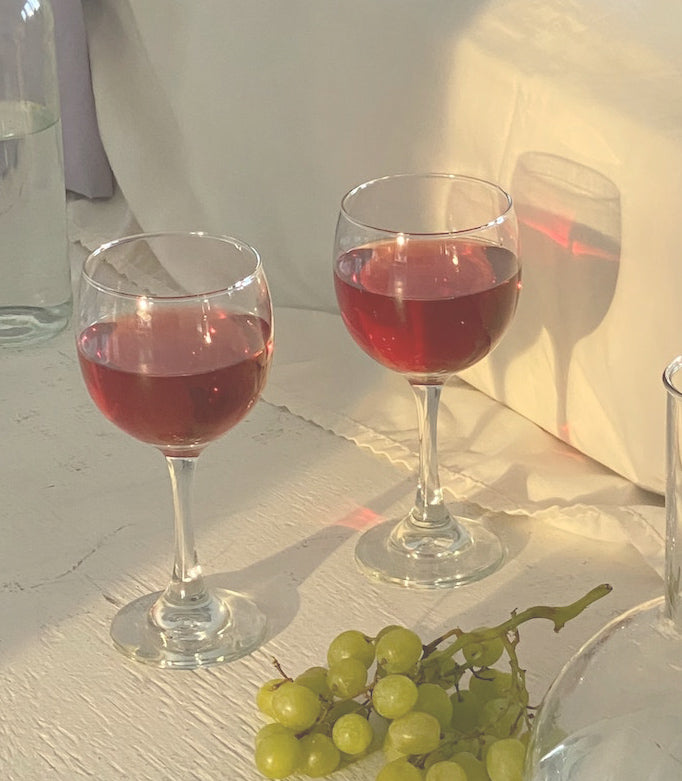 Glasses of pinot noir beside green grapes