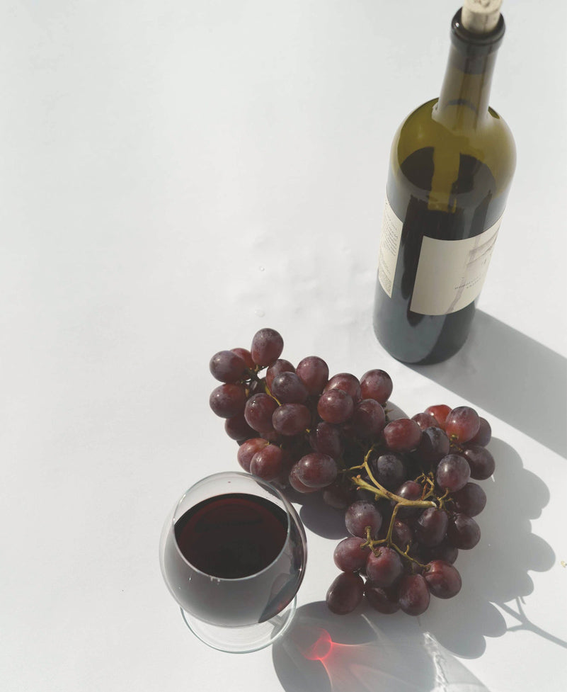 a glass and a bottle of cabernet sauvignon with grapes