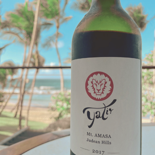 Yatir Winery Mt. Amasa wine bottle with a beach and palm trees in the background.
