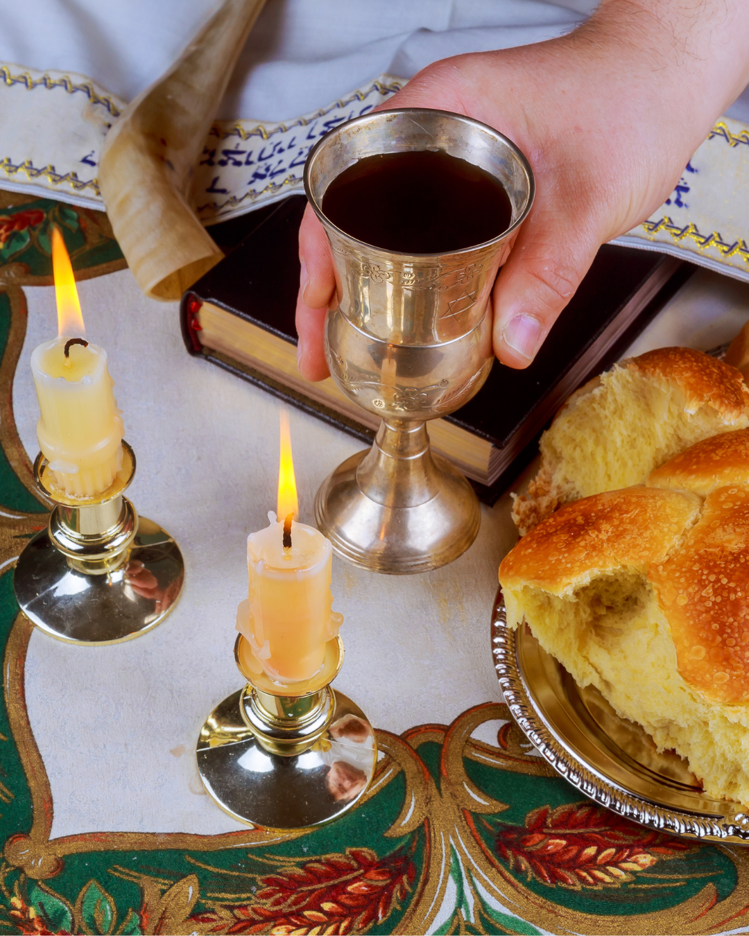 Shabbat eve table with uncovered challah bread, Sabbath candles and Kiddush wine cup