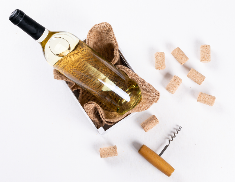 Wine bottle in a burlap-lined box with corks and a corkscrew