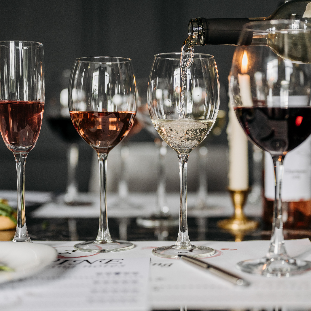 Wine glasses being filled with red and white wine on a table.