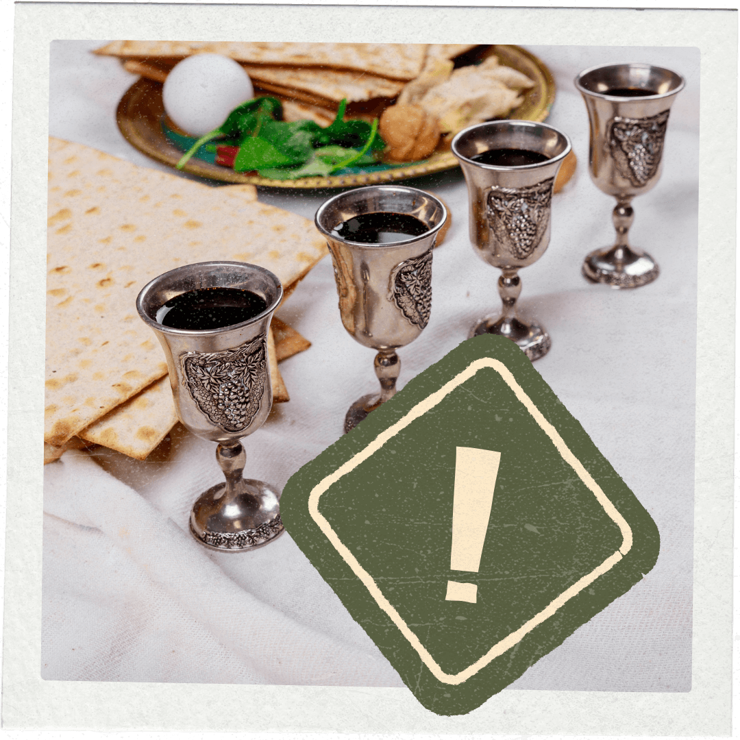 Silver kiddush cups with wine, matzah, and a green warning sign with an exclamation mark on a white surface.