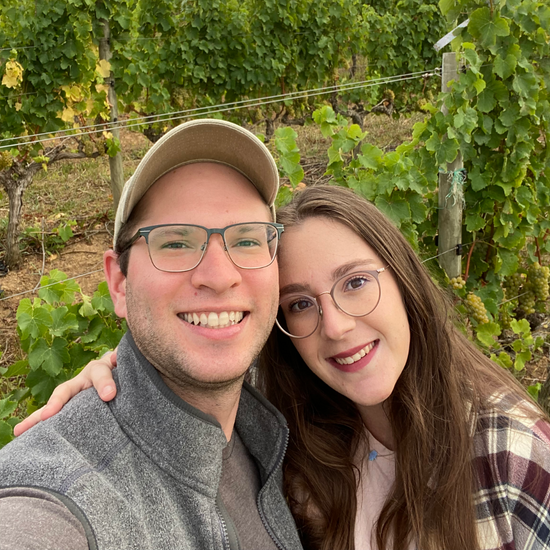 A smiling couple taking a selfie in a vineyard.