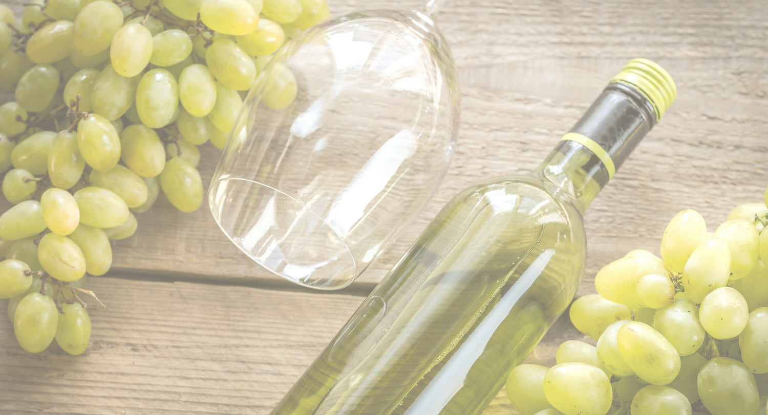 A bottle of moscato with an empty glass and green grapes
