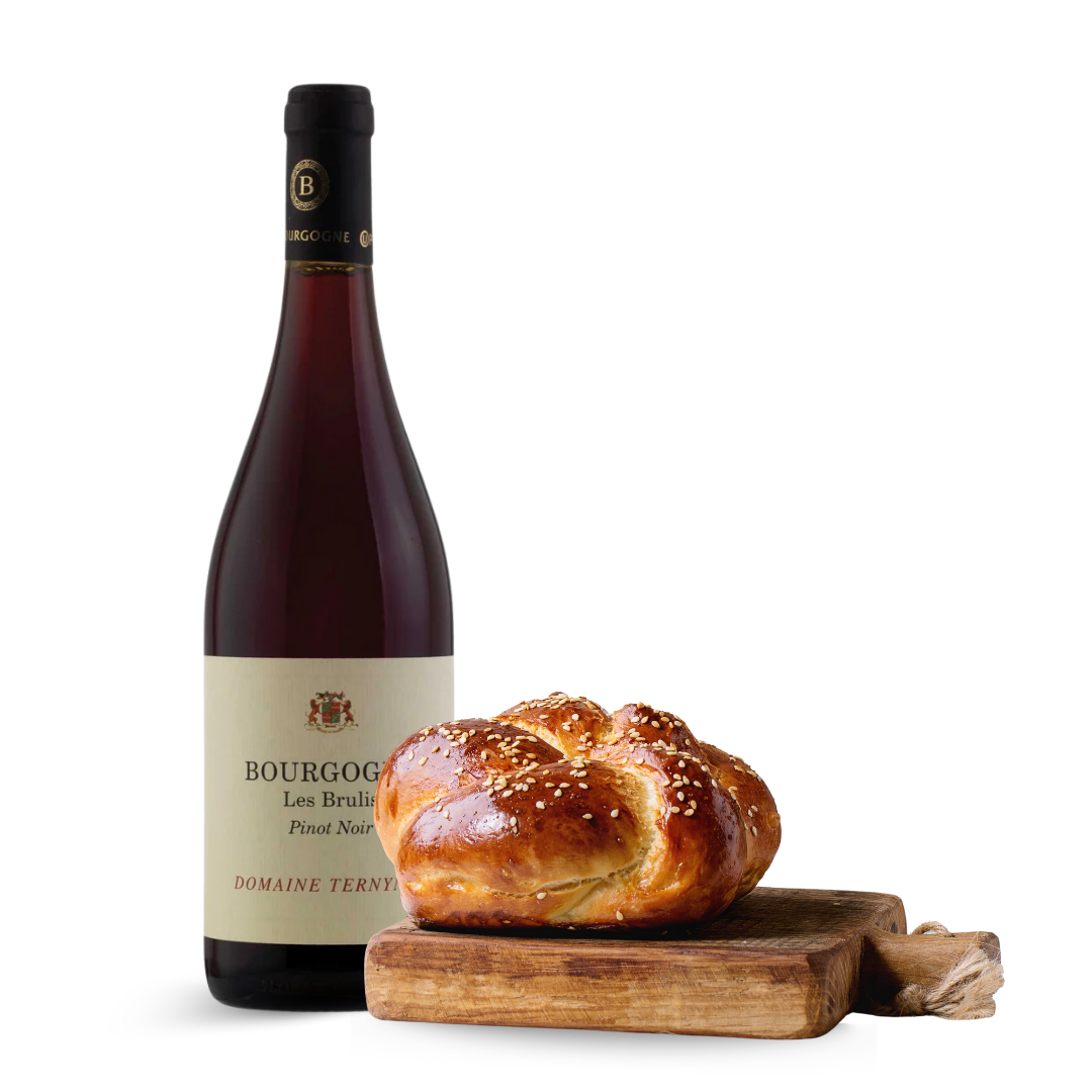 Bottle of wine with a challah bread on a wooden board against a white background
