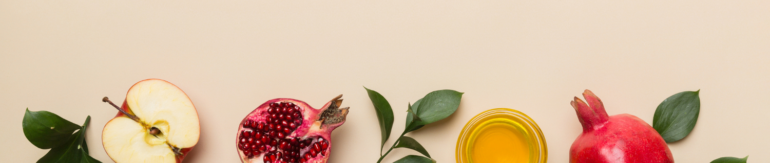 A variety of Rosh Hashanah symbols, including apple slices, pomegranates, and honey, arranged on a light background.