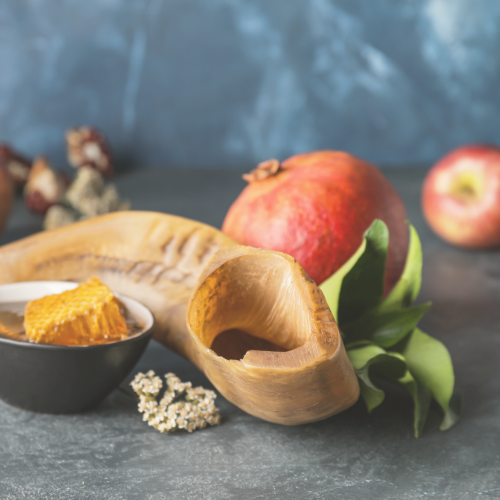 Shofar with honeycomb, apples, and pomegranate, symbolizing Rosh Hashanah traditions.