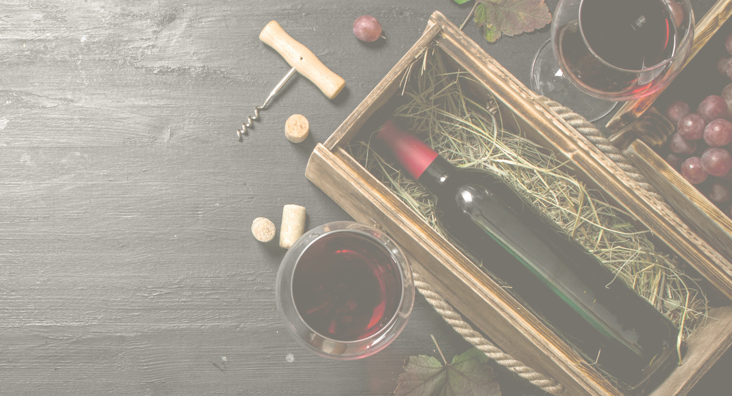 wine bottle in a crate beside grapes and glasses