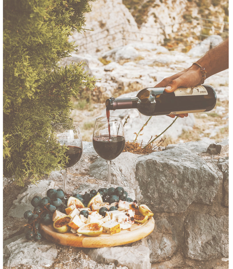 wine being poured beside a board with fruits and cheeses