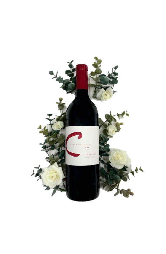 Bottle of Covenant Red C kosher wine with bouquet of white roses directly behind.