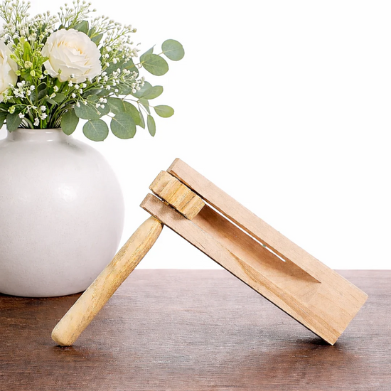 Wooden bottle opener on a wooden surface with a vase of flowers in the background
