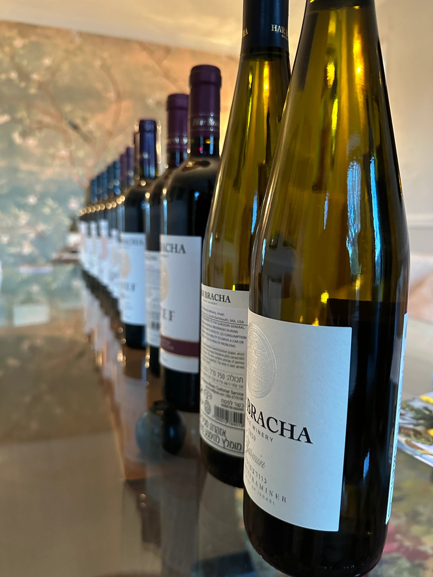 Row of wine bottles on a reflective surface with a blurred background