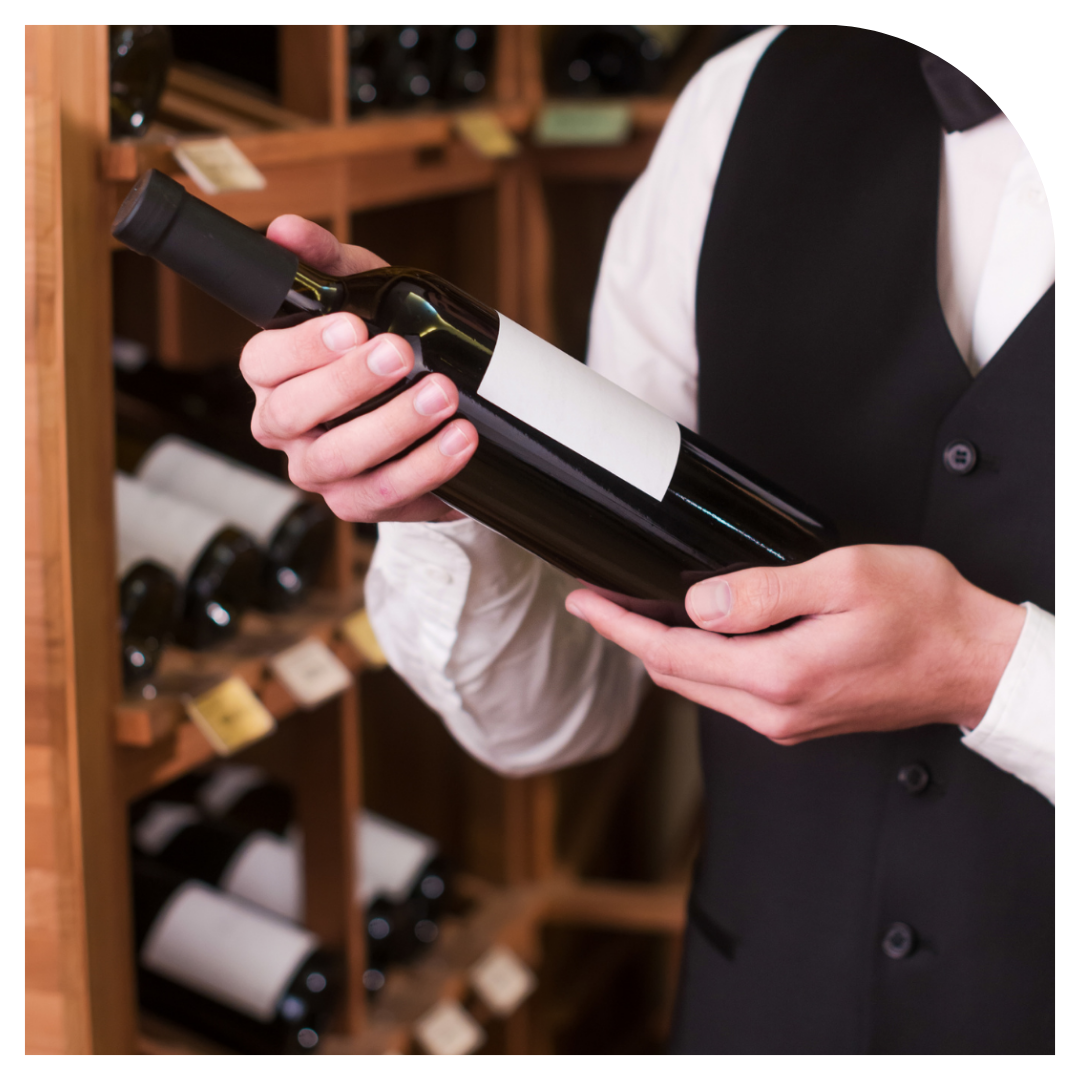 Person holding a wine bottle in a wine cellar setting