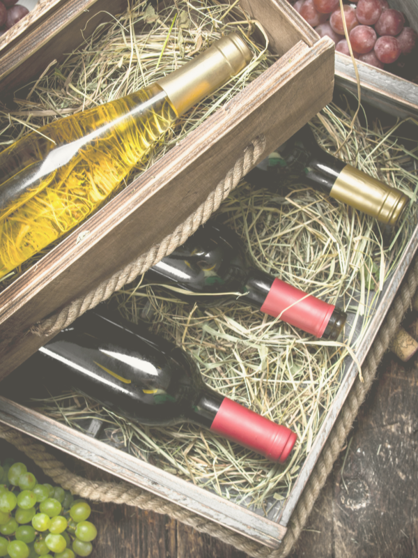 bottles of red and white wine in boxes with a wooden background